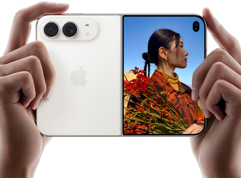 iPhone Duo, warna Putih Star White, dipegang dengan dua tangan dalam orientasi horizontal, tidak dilipat, panel kiri menampilkan kamera belakang Dual Fusion 48 MP, panel kanan menampilkan seseorang yang sedang difoto di layar luar, subjek foto dapat melihat wajahnya saat difoto menggunakan Duo Preview