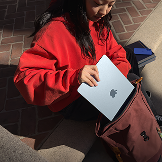 Seorang siswa memasukkan MacBook Air 15" ke dalam ranselnya