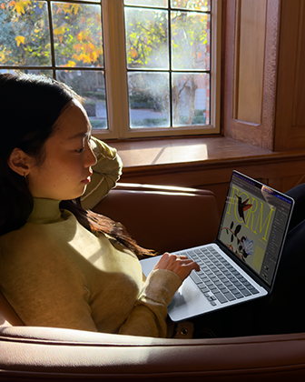 Seseorang sedang duduk di kursi sambil menggunakan MacBook Air