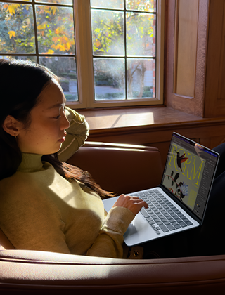 Seseorang sedang duduk di kursi sambil menggunakan MacBook Air