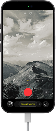 iPhone 18 Pro, eksterior depan, menampilkan lanskap bergunung, dengan overlay mode kamera dalam mode Selang Waktu, dengan kabel daya terpasang ke port pengisian daya