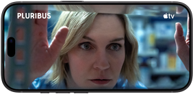 iPhone 18 Pro, mode lanskap, menampilkan close-up seorang perempuan yang melihat ke luar jendela. Judul serial: Pluribus