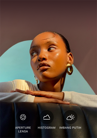 Potret close up seorang model dengan pencahayaan terang dan latar belakang penuh warna, menunjukkan UI kontrol Pro pada sistem kamera pro: Aperture, Histogram, Imbang Putih