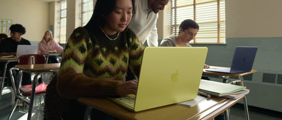 Seorang mahasiswa menggunakan MacBook Neo, warna citrus, tidak dicolok di ruang kelas