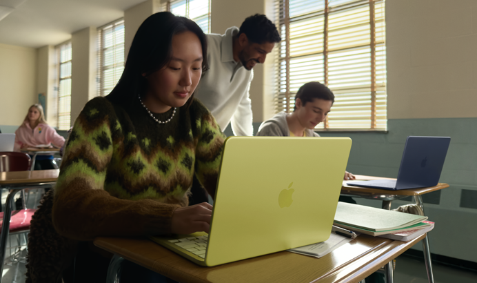 Seorang mahasiswa menggunakan MacBook Neo, warna citrus, tidak dicolok di ruang kelas
