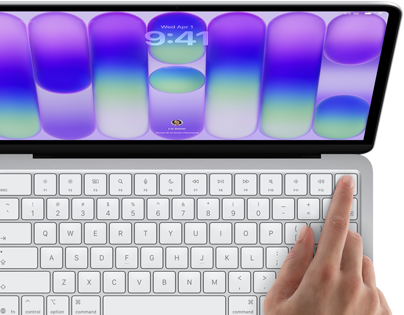 MacBook Neo, warna silver, menampilkan layar masuk, jari seseorang pada sensor Touch ID di sudut kanan atas keyboard