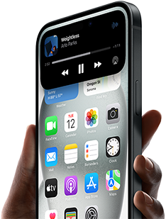 iPhone 15 yang sedang dipegang, Dynamic Island  yang menampilkan informasi pelacakan transportasi online.
